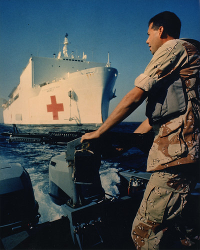 Navy corpsmen on a boat looking at a hospital ship