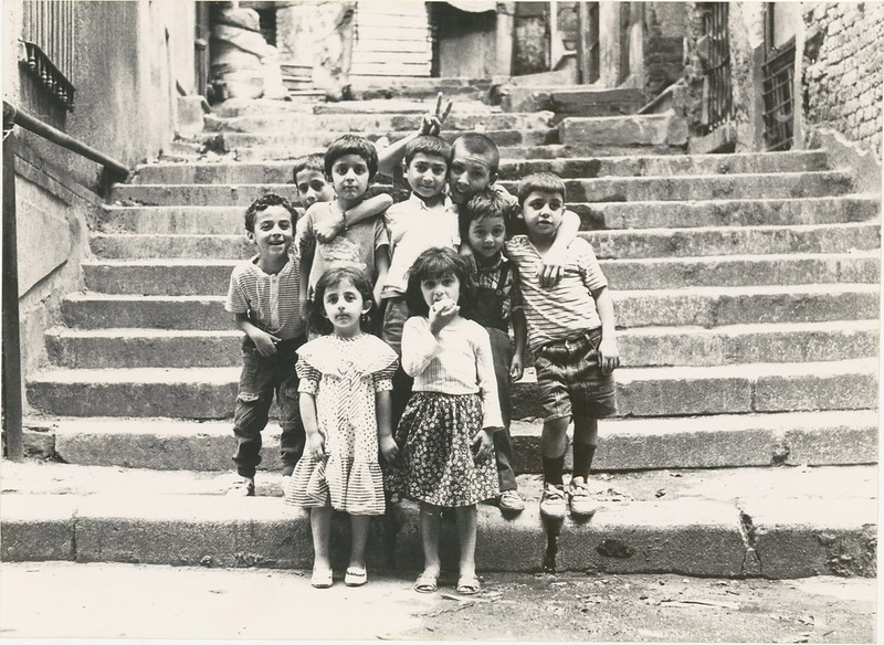 a collection of young turkish children gather on a set of steps and look at the photographer