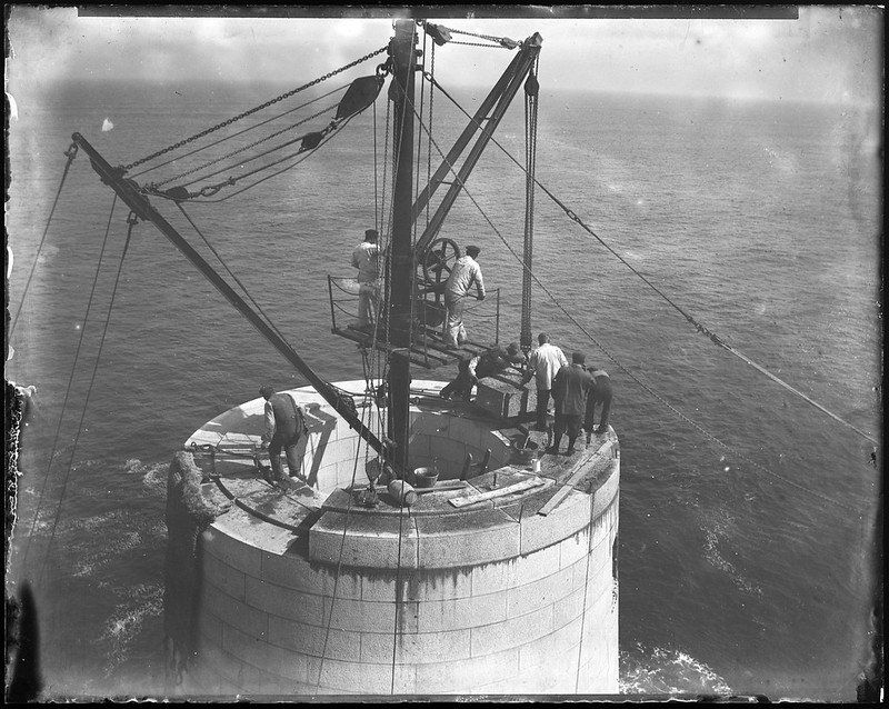 men at work building a lighthouse in the open ocean