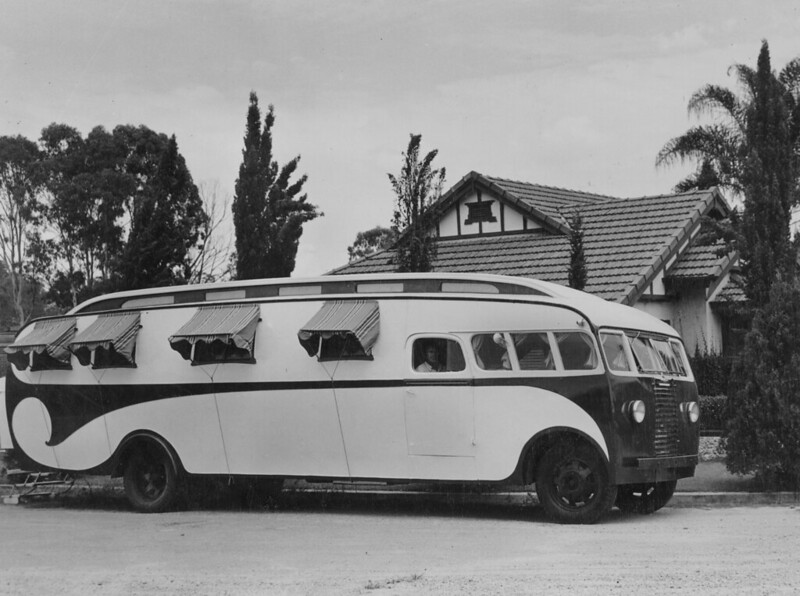 Streamlined mobile home which looks like a very curvy school bus with window awnings on the side and a racing stripe, on a Brisbane suburban street