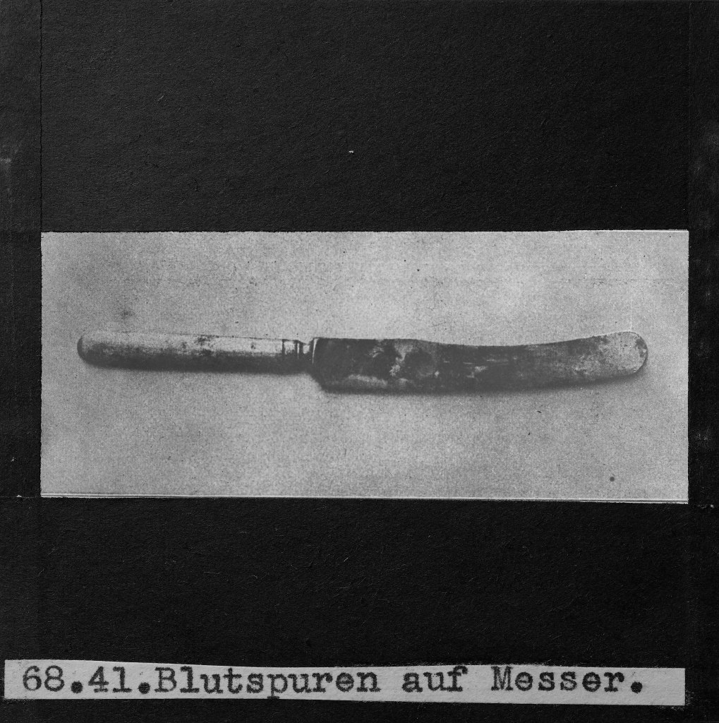 black and white image of a straight razor with bloodstains on it.